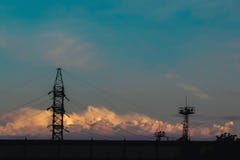 Πυλώνες ηλεκτρικής ενέργειας, ηλεκτροφόρα καλώδια που σκιαγραφούνται ενάντια σε έναν νεφελώδη ουρανό στο ηλιοβασίλεμα στοκ εικόνα με δικαίωμα ελεύθερης χρήσης Πυλώνες ηλεκτρικής ενέργειας, ηλεκτροφόρα καλώδια που σκιαγραφούνται ενάντια σε έναν νεφελώδη ουρανό στο ηλιοβασίλεμα στοκ εικόνα με δικαίωμα ελεύθερης χρήσης