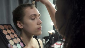 Πυροβολισμός του visagist που εφαρμόζει το ίδρυμα makeup απόθεμα βίντεο Πυροβολισμός του visagist που εφαρμόζει το ίδρυμα makeup απόθεμα βίντεο