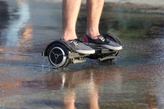 Πόδια γύρου ενός ατόμου σε έναν segway στην υγρή άσφαλτο στοκ εικόνες Πόδια γύρου ενός ατόμου σε έναν segway στην υγρή άσφαλτο στοκ εικόνες