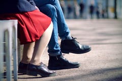 Πόδια μιας νέας συνεδρίασης ζευγών μια θερινή ημέρα σε έναν πάγκο στοκ φωτογραφίες Πόδια μιας νέας συνεδρίασης ζευγών μια θερινή ημέρα σε έναν πάγκο στοκ φωτογραφίες