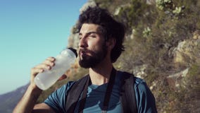Πόσιμο νερό οδοιπόρων στεμένος στο βουνό ενάντια στον ουρανό απόθεμα βίντεο Πόσιμο νερό οδοιπόρων στεμένος στο βουνό ενάντια στον ουρανό απόθεμα βίντεο