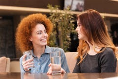 Πόσιμο νερό δύο ευτυχές ελκυστικό νέο γυναικών στον καφέ στοκ εικόνα με δικαίωμα ελεύθερης χρήσης Πόσιμο νερό δύο ευτυχές ελκυστικό νέο γυναικών στον καφέ στοκ εικόνα με δικαίωμα ελεύθερης χρήσης