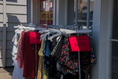 Ράφι των ενδυμάτων των γυναικών με τα κόκκινα σημάδια πώλησης εκρήξεων έξω σε ένα πεζοδρόμιο μπροστά από ένα κατάστημα ιματισμού στοκ εικόνες με δικαίωμα ελεύθερης χρήσης Ράφι των ενδυμάτων των γυναικών με τα κόκκινα σημάδια πώλησης εκρήξεων έξω σε ένα πεζοδρόμιο μπροστά από ένα κατάστημα ιματισμού στοκ εικόνες με δικαίωμα ελεύθερης χρήσης