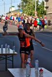 Ρήγα, Λετονία - 19 Μαΐου 2019: Καυκάσιο θηλυκό αθλητικό ποτό αρπαγής δρομέων ελίτ με τη μεγάλη ταχύτητα στοκ εικόνα με δικαίωμα ελεύθερης χρήσης Ρήγα, Λετονία - 19 Μαΐου 2019: Καυκάσιο θηλυκό αθλητικό ποτό αρπαγής δρομέων ελίτ με τη μεγάλη ταχύτητα στοκ εικόνα με δικαίωμα ελεύθερης χρήσης
