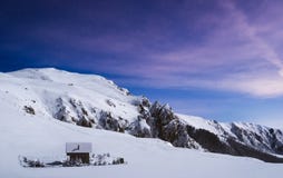 Ρομαντική καμπίνα κούτσουρων πάνω από το χιονώδες βουνό που φωτογραφίζεται τη νύχτα στοκ εικόνες Ρομαντική καμπίνα κούτσουρων πάνω από το χιονώδες βουνό που φωτογραφίζεται τη νύχτα στοκ εικόνες