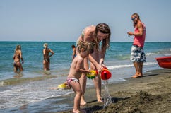 ΡΩΜΗ, ΙΤΑΛΙΑ - ΤΟΝ ΙΟΎΛΙΟ ΤΟΥ 2017: Μια νέες οικογένεια, μια μητέρα και μια κόρη με έναν κολυμπώντας κύκλο, που παίζει στην παραλ στοκ φωτογραφία με δικαίωμα ελεύθερης χρήσης ΡΩΜΗ, ΙΤΑΛΙΑ - ΤΟΝ ΙΟΎΛΙΟ ΤΟΥ 2017: Μια νέες οικογένεια, μια μητέρα και μια κόρη με έναν κολυμπώντας κύκλο, που παίζει στην παραλ στοκ φωτογραφία με δικαίωμα ελεύθερης χρήσης