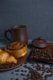 Ρόλος με την κανέλα και croissant σε ένα γκρίζο υπόβαθρο και ένα φλιτζάνι του καφέ με έναν φραγμό σοκολάτας στοκ εικόνα με δικαίωμα ελεύθερης χρήσης Ρόλος με την κανέλα και croissant σε ένα γκρίζο υπόβαθρο και ένα φλιτζάνι του καφέ με έναν φραγμό σοκολάτας στοκ εικόνα με δικαίωμα ελεύθερης χρήσης