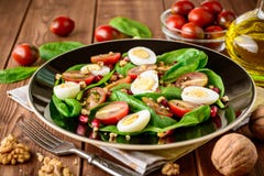 Σαλάτα φρέσκων λαχανικών με το σπανάκι, τις ντομάτες κερασιών, τα αυγά ορτυκιών, τους σπόρους ροδιών και τα ξύλα καρυδιάς στο μαύ Στοκ Εικόνα Σαλάτα φρέσκων λαχανικών με το σπανάκι, τις ντομάτες κερασιών, τα αυγά ορτυκιών, τους σπόρους ροδιών και τα ξύλα καρυδιάς στο μαύ Στοκ Εικόνα