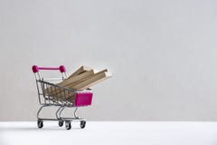 Σε ένα άσπρο πάτωμα σε ένα άσπρο υπόβαθρο υπάρχει ένα καροτσάκι αγορών με τους ξύλινους φραγμούς των πινάκων στοκ εικόνα Σε ένα άσπρο πάτωμα σε ένα άσπρο υπόβαθρο υπάρχει ένα καροτσάκι αγορών με τους ξύλινους φραγμούς των πινάκων στοκ εικόνα