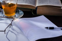 Σημειωματάριο με τα εγχειρίδια δίπλα σε ένα φλυτζάνι του τσαγιού και των γυαλιών στα ξημερώματα στοκ φωτογραφία με δικαίωμα ελεύθερης χρήσης Σημειωματάριο με τα εγχειρίδια δίπλα σε ένα φλυτζάνι του τσαγιού και των γυαλιών στα ξημερώματα στοκ φωτογραφία με δικαίωμα ελεύθερης χρήσης