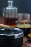 Σιγοκαίγοντας πούρο που βρίσκεται ashtray Στο υπόβαθρο σε μια defocusing κούπα στοκ φωτογραφία με δικαίωμα ελεύθερης χρήσης Σιγοκαίγοντας πούρο που βρίσκεται ashtray Στο υπόβαθρο σε μια defocusing κούπα στοκ φωτογραφία με δικαίωμα ελεύθερης χρήσης