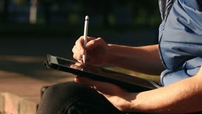 Σκίτσο σχεδίων σχεδιαστών στην ταμπλέτα που χρησιμοποιεί stylus στο πάρκο απόθεμα βίντεο Σκίτσο σχεδίων σχεδιαστών στην ταμπλέτα που χρησιμοποιεί stylus στο πάρκο απόθεμα βίντεο