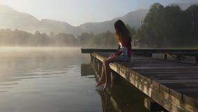 Σκεπτική γυναίκα στην αποβάθρα της λίμνης βουνών απόθεμα βίντεο Σκεπτική γυναίκα στην αποβάθρα της λίμνης βουνών απόθεμα βίντεο
