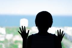 Σκιαγραφήστε ένα μικρό αγόρι που εξετάζει θάλασσα το παράθυρο στοκ εικόνες Σκιαγραφήστε ένα μικρό αγόρι που εξετάζει θάλασσα το παράθυρο στοκ εικόνες