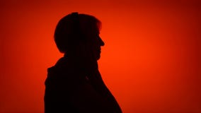Σκιαγραφία της ανώτερης γυναίκας που τίθεται στα ακουστικά στο κόκκινο υπόβαθρο Το θηλυκό στο σχεδιάγραμμα ακούει τη μουσική φιλμ μικρού μήκους Σκιαγραφία της ανώτερης γυναίκας που τίθεται στα ακουστικά στο κόκκινο υπόβαθρο Το θηλυκό στο σχεδιάγραμμα ακούει τη μουσική φιλμ μικρού μήκους