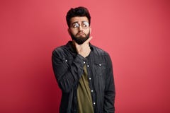 Σοβαρό ελκυστικό γενειοφόρο μοντέρνο άτομο σχετικά με το πηγούνι και εξέταση κατά μέρος τη κάμερα στοκ φωτογραφία Σοβαρό ελκυστικό γενειοφόρο μοντέρνο άτομο σχετικά με το πηγούνι και εξέταση κατά μέρος τη κάμερα στοκ φωτογραφία
