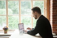 Σοβαρός επιχειρηματίας που εργάζεται στο lap-top που αναλύει το πρόγραμμα Στοκ Φωτογραφία Σοβαρός επιχειρηματίας που εργάζεται στο lap-top που αναλύει το πρόγραμμα Στοκ Φωτογραφία