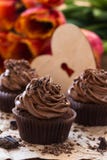 Σοκολάτα ημέρας μητέρων cupcakes με τις τουλίπες άνοιξη και το ξύλινο χ στοκ φωτογραφίες Σοκολάτα ημέρας μητέρων cupcakes με τις τουλίπες άνοιξη και το ξύλινο χ στοκ φωτογραφίες