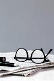 Σπάσιμο εφημερίδων με τη μάνδρα και τα γυαλιά Στοκ Εικόνα Σπάσιμο εφημερίδων με τη μάνδρα και τα γυαλιά Στοκ Εικόνα