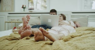 Στην κρεβατοκάμαρα ένα χαριτωμένο ζεύγος που ξοδεύει έναν ρομαντικό χρόνο που προσέχει μαζί κάτι από το σημειωματάριο μετά από έν απόθεμα βίντεο Στην κρεβατοκάμαρα ένα χαριτωμένο ζεύγος που ξοδεύει έναν ρομαντικό χρόνο που προσέχει μαζί κάτι από το σημειωματάριο μετά από έν απόθεμα βίντεο
