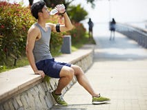 Στηργμένος και πόσιμο νερό νέου ασιατικού jogger στοκ εικόνες Στηργμένος και πόσιμο νερό νέου ασιατικού jogger στοκ εικόνες