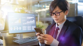 Στις χρήσεις Smartphone, ΟΜΠ ανατολικών ασιατικές επιχειρηματιών γραφείων δακτυλογράφησης στοκ εικόνα με δικαίωμα ελεύθερης χρήσης Στις χρήσεις Smartphone, ΟΜΠ ανατολικών ασιατικές επιχειρηματιών γραφείων δακτυλογράφησης στοκ εικόνα με δικαίωμα ελεύθερης χρήσης