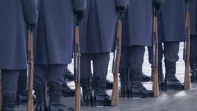 Στρατιώτες στις μπλε στολές και τις μαύρες μπότες, που κρατούν ένα πυροβόλο όπλο και που στέκονται σε μια γραμμή φιλμ μικρού μήκους Στρατιώτες στις μπλε στολές και τις μαύρες μπότες, που κρατούν ένα πυροβόλο όπλο και που στέκονται σε μια γραμμή φιλμ μικρού μήκους