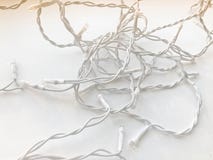 Στριμμένα άσπρα καλώδια μιας γιρλάντας στην άσπρη λαστιχένια μόνωση με τις λάμπες φωτός σε ένα άσπρο υπόβαθρο στοκ φωτογραφία με δικαίωμα ελεύθερης χρήσης Στριμμένα άσπρα καλώδια μιας γιρλάντας στην άσπρη λαστιχένια μόνωση με τις λάμπες φωτός σε ένα άσπρο υπόβαθρο στοκ φωτογραφία με δικαίωμα ελεύθερης χρήσης