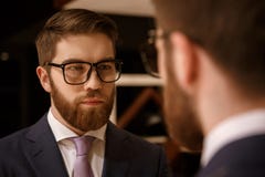 Συγκεντρωμένος νέος γενειοφόρος επιχειρηματίας που εξετάζει τον καθρέφτη στοκ φωτογραφία με δικαίωμα ελεύθερης χρήσης Συγκεντρωμένος νέος γενειοφόρος επιχειρηματίας που εξετάζει τον καθρέφτη στοκ φωτογραφία με δικαίωμα ελεύθερης χρήσης