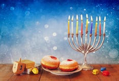 Συγκρατημένη εικόνα των εβραϊκών διακοπών Hanukkah με το menorah, doughnuts και τα ξύλινα dreidels (περιστρεφόμενη κορυφή) αναδρο Συγκρατημένη εικόνα των εβραϊκών διακοπών Hanukkah με το menorah, doughnuts και τα ξύλινα dreidels (περιστρεφόμενη κορυφή) αναδρο