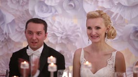Συνεδρίαση Newlyweds σε έναν πίνακα στο γάμο της που επιδοκιμάζει και που χαμογελά κοντά επάνω απόθεμα βίντεο Συνεδρίαση Newlyweds σε έναν πίνακα στο γάμο της που επιδοκιμάζει και που χαμογελά κοντά επάνω απόθεμα βίντεο