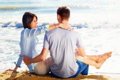 Συνεδρίαση ζεύγους στην άμμο στην παραλία που φαίνεται η θάλασσα στοκ εικόνα Συνεδρίαση ζεύγους στην άμμο στην παραλία που φαίνεται η θάλασσα στοκ εικόνα