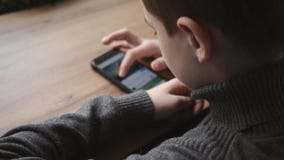 Συνεδρίαση αγοριών εφήβων από το παράθυρο σε έναν καφέ με ένα smartphone στα χέρια του Επικοινωνία στα κοινωνικά δίκτυα Παιχνίδια απόθεμα βίντεο Συνεδρίαση αγοριών εφήβων από το παράθυρο σε έναν καφέ με ένα smartphone στα χέρια του Επικοινωνία στα κοινωνικά δίκτυα Παιχνίδια απόθεμα βίντεο