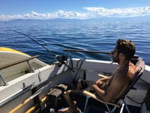 συνεδρίαση ατόμων και χαλάρωση στην πρύμνη της βάρκας του όπως αλιεύει για στοκ εικόνες συνεδρίαση ατόμων και χαλάρωση στην πρύμνη της βάρκας του όπως αλιεύει για στοκ εικόνες