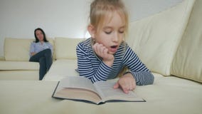 Συνεδρίαση βιβλίων ανάγνωσης μητέρων και κορών στον καναπέ στο σπίτι απόθεμα βίντεο Συνεδρίαση βιβλίων ανάγνωσης μητέρων και κορών στον καναπέ στο σπίτι απόθεμα βίντεο