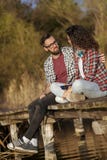 Συνεδρίαση ζεύγους στις αποβάθρες λιμνών στοκ εικόνες Συνεδρίαση ζεύγους στις αποβάθρες λιμνών στοκ εικόνες