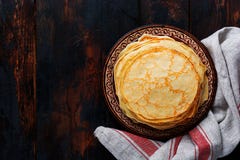 Σωρός των σπιτικών λεπτών τηγανιτών με τα κομμάτια του βουτύρου, του γάλακτος και του μελιού στο παλαιό αγροτικό κεραμικό πιάτο στοκ φωτογραφία με δικαίωμα ελεύθερης χρήσης Σωρός των σπιτικών λεπτών τηγανιτών με τα κομμάτια του βουτύρου, του γάλακτος και του μελιού στο παλαιό αγροτικό κεραμικό πιάτο στοκ φωτογραφία με δικαίωμα ελεύθερης χρήσης