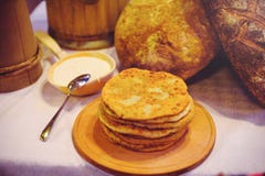Σωρός των τηγανιτών αέρα σε ένα ξύλινο dinette, μια παραδοσιακή οικογένεια τροφίμων τηγανίτες του χρυσού χρώματος, ξινή κρέμα στο στοκ φωτογραφία με δικαίωμα ελεύθερης χρήσης Σωρός των τηγανιτών αέρα σε ένα ξύλινο dinette, μια παραδοσιακή οικογένεια τροφίμων τηγανίτες του χρυσού χρώματος, ξινή κρέμα στο στοκ φωτογραφία με δικαίωμα ελεύθερης χρήσης