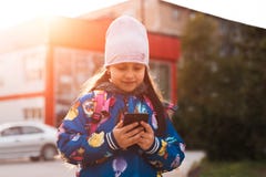 Σύγχρονο smartphone χρήσης κοριτσιών παιδιών σε υπαίθριο με το φως του ήλιου στοκ φωτογραφίες Σύγχρονο smartphone χρήσης κοριτσιών παιδιών σε υπαίθριο με το φως του ήλιου στοκ φωτογραφίες
