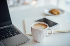 Σύγχρονο άσπρο γραφείο, χειροποίητο φλυτζάνι σχεδιαστών με τον καφέ, smartpho στοκ εικόνα με δικαίωμα ελεύθερης χρήσης Σύγχρονο άσπρο γραφείο, χειροποίητο φλυτζάνι σχεδιαστών με τον καφέ, smartpho στοκ εικόνα με δικαίωμα ελεύθερης χρήσης