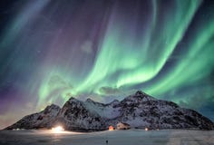 Τα borealis αυγής με έναστρο πέρα από τη σειρά βουνών χιονιού με το φωτισμό στεγάζουν σε Flakstad, νησιά Lofoten, Νορβηγία στοκ εικόνες με δικαίωμα ελεύθερης χρήσης Τα borealis αυγής με έναστρο πέρα από τη σειρά βουνών χιονιού με το φωτισμό στεγάζουν σε Flakstad, νησιά Lofoten, Νορβηγία στοκ εικόνες με δικαίωμα ελεύθερης χρήσης