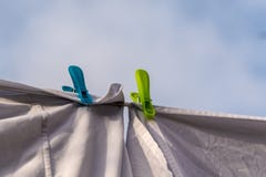 Τα άσπρα ενδύματα κρέμασαν έξω για να ξεράνουν σε μια γραμμή πλύσης και στερεωμένος από τους γόμφους ενδυμάτων ενάντια στο μπλε ο στοκ εικόνες με δικαίωμα ελεύθερης χρήσης Τα άσπρα ενδύματα κρέμασαν έξω για να ξεράνουν σε μια γραμμή πλύσης και στερεωμένος από τους γόμφους ενδυμάτων ενάντια στο μπλε ο στοκ εικόνες με δικαίωμα ελεύθερης χρήσης