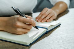 Τα θηλυκά χέρια γράφουν σε ένα σημειωματάριο στοκ εικόνα Τα θηλυκά χέρια γράφουν σε ένα σημειωματάριο στοκ εικόνα