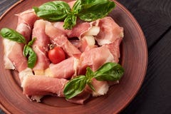 Τα μικρά κομμάτια του ανανά κύλησαν στο iberico ή το proscuitto jamon με τις ντομάτες και spanac τα φύλλα κερασιών σε ένα πιάτο στοκ εικόνα Τα μικρά κομμάτια του ανανά κύλησαν στο iberico ή το proscuitto jamon με τις ντομάτες και spanac τα φύλλα κερασιών σε ένα πιάτο στοκ εικόνα