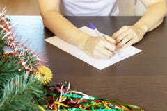 Τα χέρια μιας συνεδρίασης γυναικών μέχρι τα Χριστούγεννα πινάκων και γραψίματος επιθυμούν σε μια κάρτα, επιστολή στοκ φωτογραφίες με δικαίωμα ελεύθερης χρήσης Τα χέρια μιας συνεδρίασης γυναικών μέχρι τα Χριστούγεννα πινάκων και γραψίματος επιθυμούν σε μια κάρτα, επιστολή στοκ φωτογραφίες με δικαίωμα ελεύθερης χρήσης