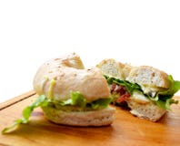 Τεμαχισμένο bagel σάντουιτς με τα λαχανικά σε έναν ξύλινο τέμνοντα πίνακα στοκ φωτογραφία με δικαίωμα ελεύθερης χρήσης Τεμαχισμένο bagel σάντουιτς με τα λαχανικά σε έναν ξύλινο τέμνοντα πίνακα στοκ φωτογραφία με δικαίωμα ελεύθερης χρήσης