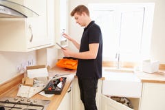 Τεχνικός που συντηρεί boiler στην κουζίνα που χρησιμοποιεί τον υπολογιστή ταμπλετών στοκ εικόνα Τεχνικός που συντηρεί boiler στην κουζίνα που χρησιμοποιεί τον υπολογιστή ταμπλετών στοκ εικόνα