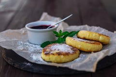 Τηγανισμένες cheesecakes ή οι τηγανίτες σε χαρτί τεχνών για το πιάτο πετρών με το βακκίνιο φράσσουν στοκ φωτογραφία Τηγανισμένες cheesecakes ή οι τηγανίτες σε χαρτί τεχνών για το πιάτο πετρών με το βακκίνιο φράσσουν στοκ φωτογραφία