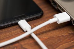 Τηλέφωνο που συνδέεται κινητό με το lap-top Ένα καλώδιο USB συνδέει το τηλέφωνο και το lap-top στον ξύλινο πίνακα Έξυπνο τηλέφωνο στοκ εικόνες Τηλέφωνο που συνδέεται κινητό με το lap-top Ένα καλώδιο USB συνδέει το τηλέφωνο και το lap-top στον ξύλινο πίνακα Έξυπνο τηλέφωνο στοκ εικόνες