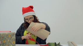 Το brunette γοητείας δένει την κόκκινη κορδέλλα γύρω από το δώρο απόθεμα βίντεο Το brunette γοητείας δένει την κόκκινη κορδέλλα γύρω από το δώρο απόθεμα βίντεο